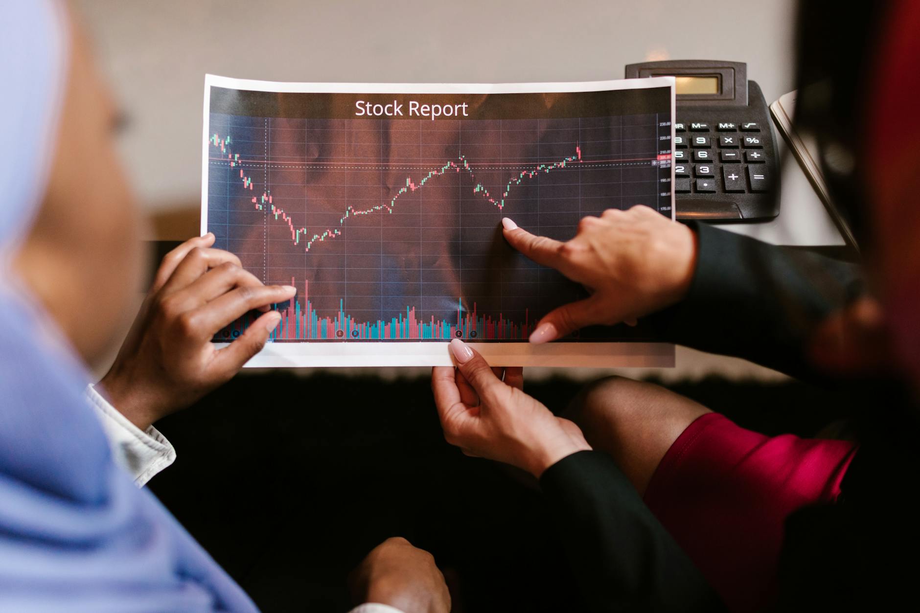 Dwóch analityków omawia wykres giełdowy podczas spotkania biznesowego