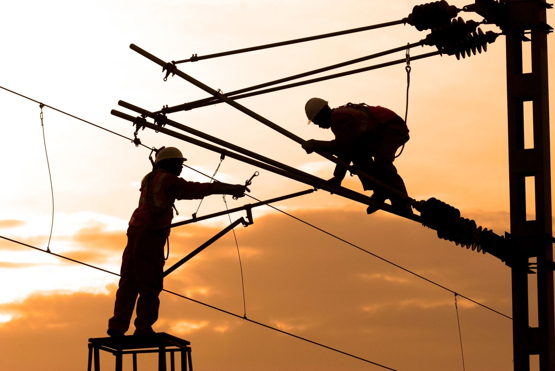 Elektrycy naprawiają linie energetyczne o zachodzie słońca