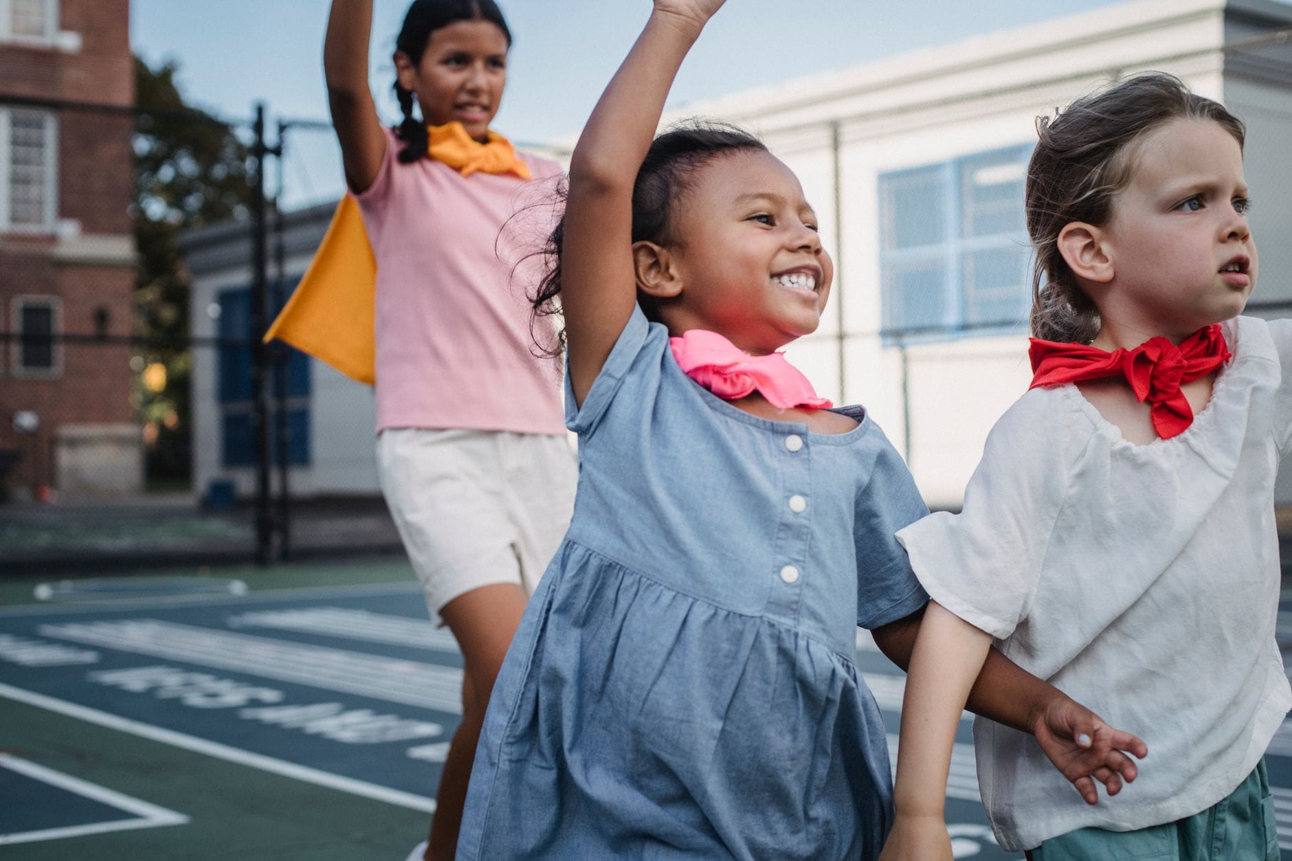 Troje dzieci bawi się w superbohaterów na słonecznym placu zabaw