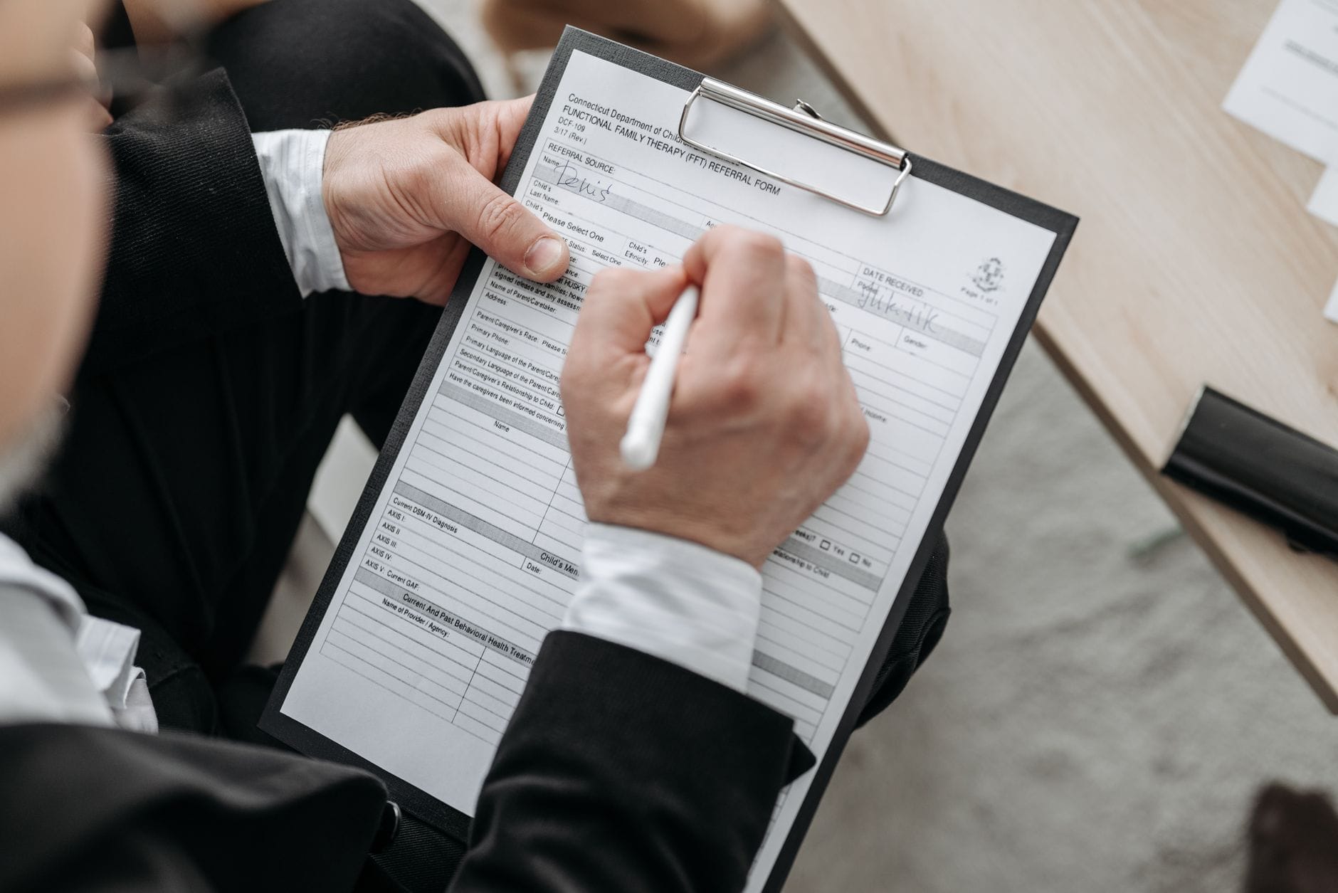Biznesmen podpisuje formalny dokument na podkładce z klipsem